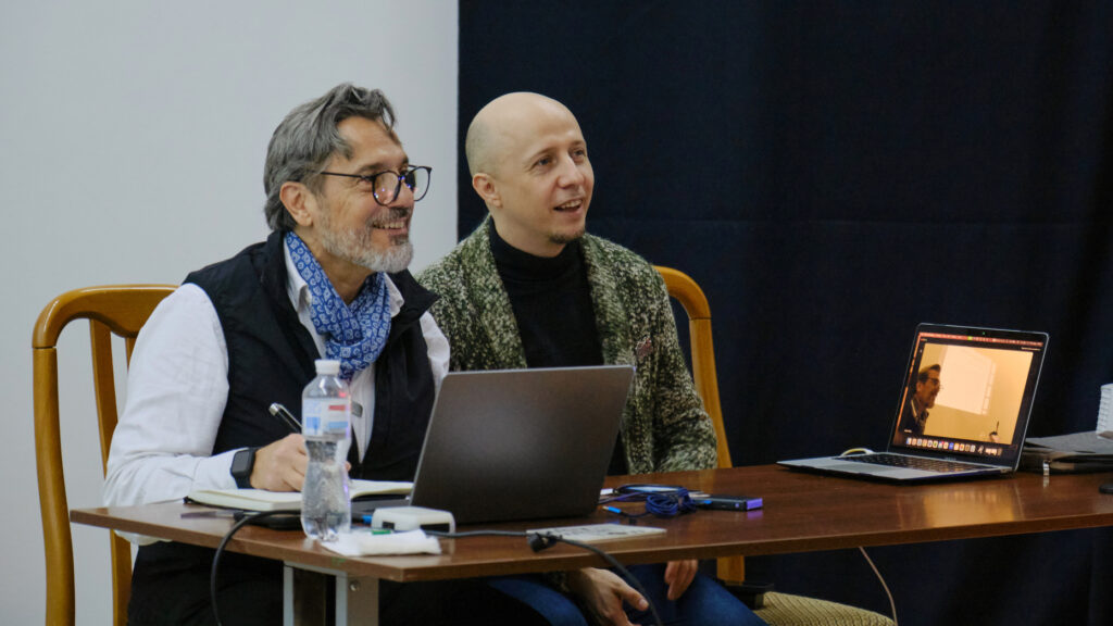 Two men sitting in a desk with open laptops